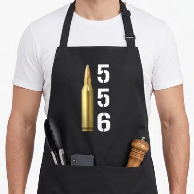 Tablier de cuisine noir avec illustration d'une cartouche 556 dorée et texte blanc vertical 556 à côté.