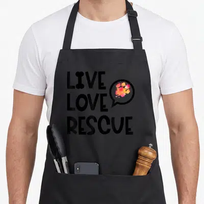 Tablier de cuisine noir avec texte Live Love Rescue et patte d'animaux colorée dans une bulle de dialogue.