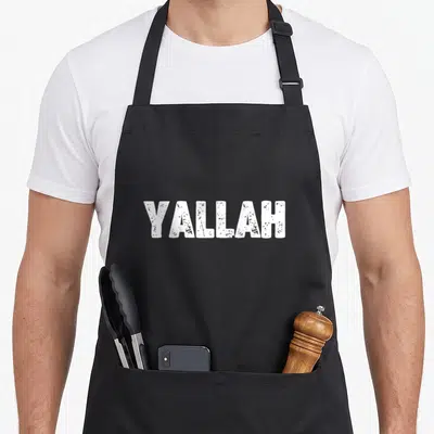 Tablier de cuisine noir avec l'inscription YALLAH en lettres blanches épaisses et texturées au centre.