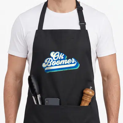 Tablier de cuisine noir avec le logo Ok Boomer en lettres blanches sur fond bleu vintage.