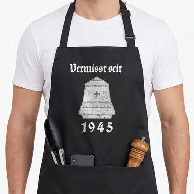 Tablier de cuisine noir avec illustration blanche de casque et texte Vermisst seit 1945 en typographie gothique.