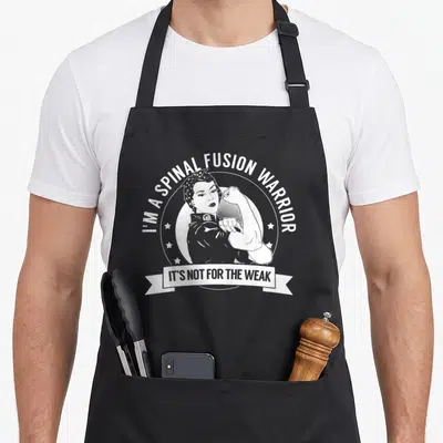 Tablier de cuisine noir avec illustration blanche d'une femme musclée et texte I'm a spinal fusion warrior.