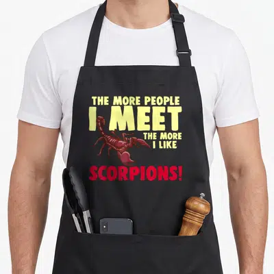 Tablier de cuisine noir avec illustration d'un scorpion rouge et texte jaune et rouge sur fond uni.