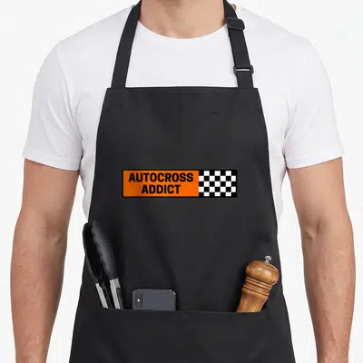 Tablier de cuisine noir avec autocollant orange AUTOCROSS ADDICT et damier de course noir blanc.