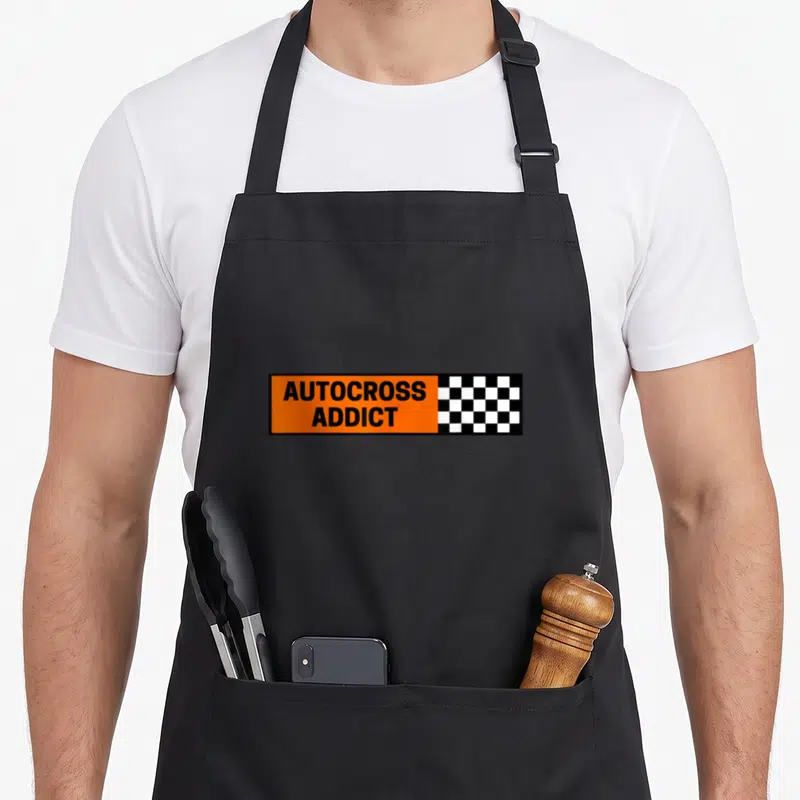 Tablier de cuisine noir avec autocollant orange AUTOCROSS ADDICT et damier de course noir blanc.