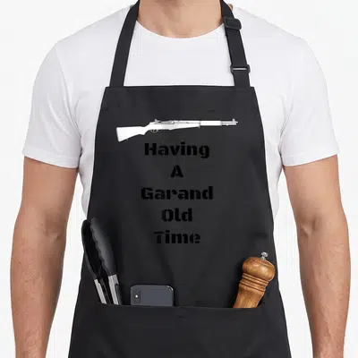 Tablier de cuisine noir avec dessin blanc fusil M1 Garand et texte Having A Garand Old Time en typographie noire.
