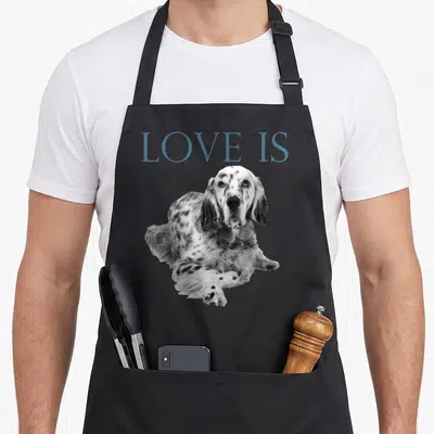 Tablier de cuisine noir avec l'inscription Love Is et la photographie d'un Setter anglais posé au centre du vêtement.