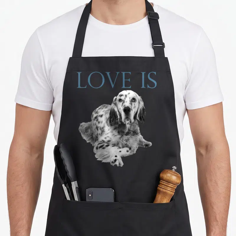 Tablier de cuisine noir avec l'inscription Love Is et la photographie d'un Setter anglais posé au centre du vêtement.
