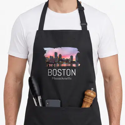 Tablier de cuisine noir avec une illustration colorée du skyline de Boston et le nom de la ville en blanc.