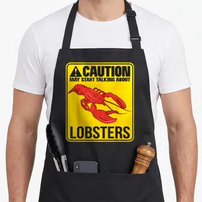 Tablier de cuisine noir avec signalisation jaune Caution May Start Talking About Lobsters et homard rouge stylisé.