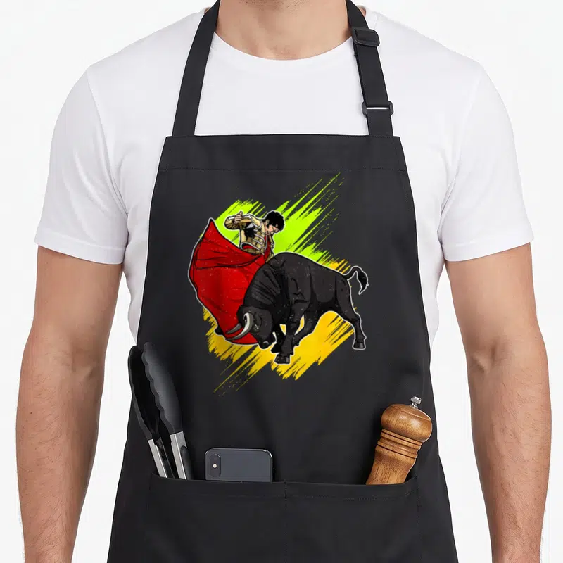 Tablier de cuisine noir avec illustration colorée d'un matador affrontant un taureau noir sous une cape rouge.