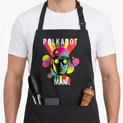 Tablier de cuisine noir avec le visage du Polkadot Man entouré de cercles colorés et de rayons lumineux.