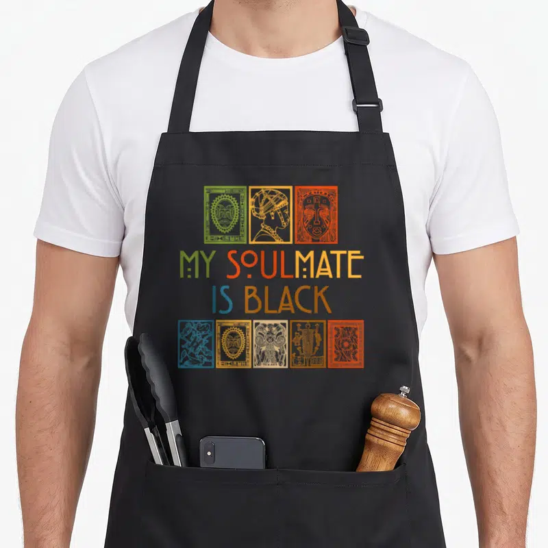 Tablier de cuisine noir avec inscription My Soulmate Is Black et illustrations de masques traditionnels multicolores.