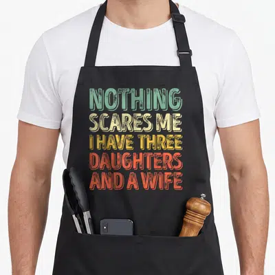 Tablier de cuisine noir avec texte multicolore « Nothing scares me I have three daughters and a wife » style rétro.