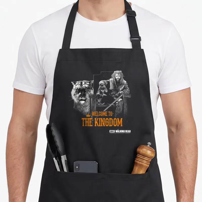 Tablier de cuisine noir avec illustration Negan, tigre et texte Welcome to the Kingdom en orange.