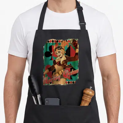Tablier de cuisine noir avec illustration Harley Quinn Bombshell tenant un pistolet et le texte Harley Quinn en bas.