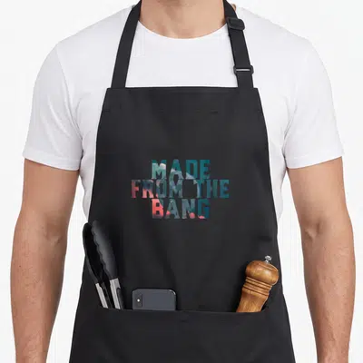 Tablier de cuisine noir avec l'inscription Made From The Bang en lettres colorées sur fond cosmique.