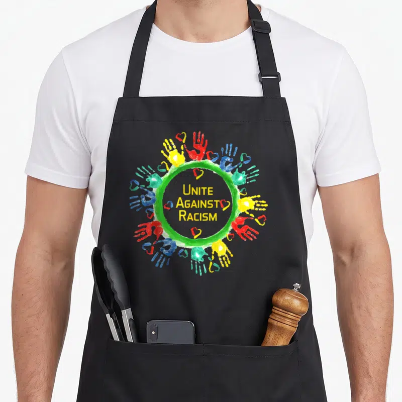Tablier de cuisine noir avec un cercle de mains multicolores et le texte Unite Against Racism au centre.