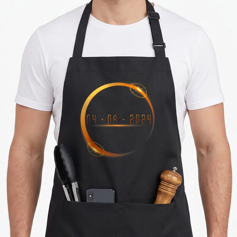 Tablier de cuisine noir avec un cercle orange lumineux et la date 04.08.2024 au centre.