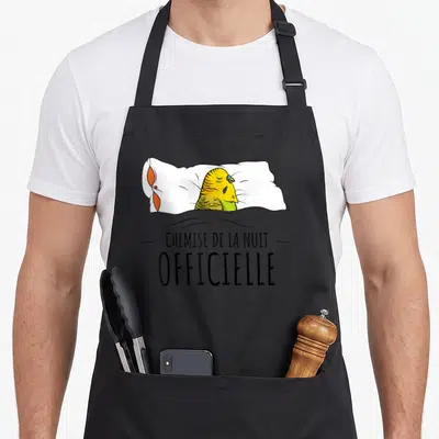 Tablier de cuisine noir avec illustration d'une perruche dans son lit et le texte « Chemise de la Nuit Officielle »
