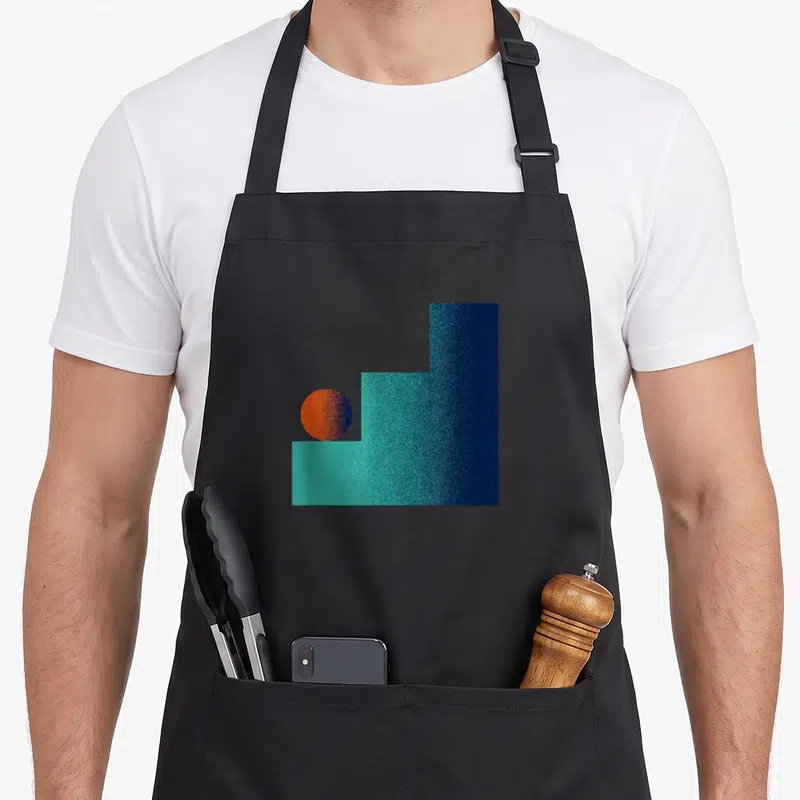 Tablier de cuisine noir avec motif d'une balle orange posée sur des escaliers turquoise texturés dans un style abstrait géométrique.
