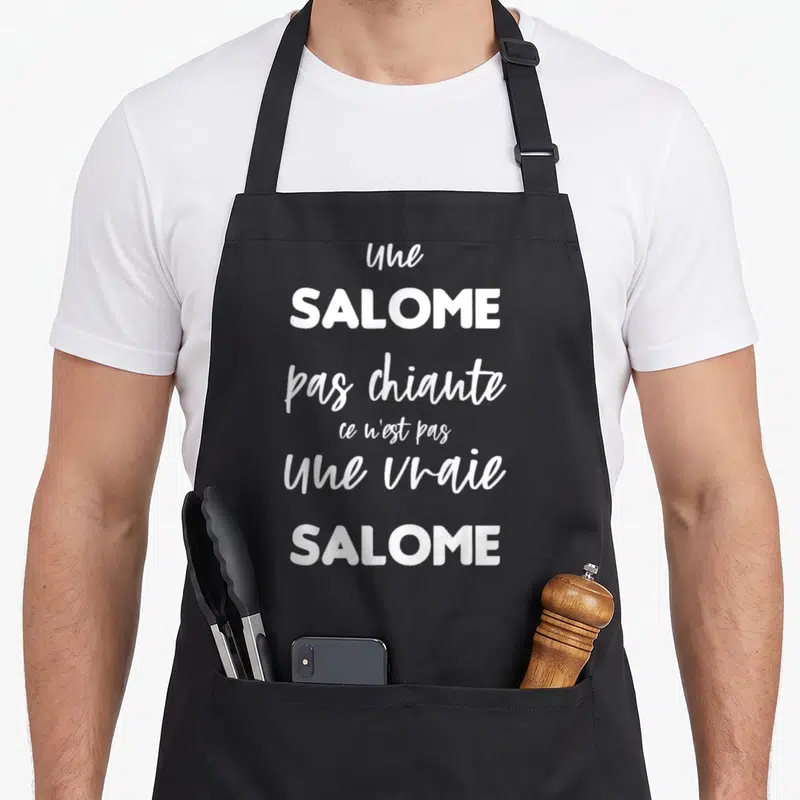 Tablier de cuisine noir avec le texte blanc une SALOME pas chiante ce n'est pas une vraie SALOME imprimé au centre.