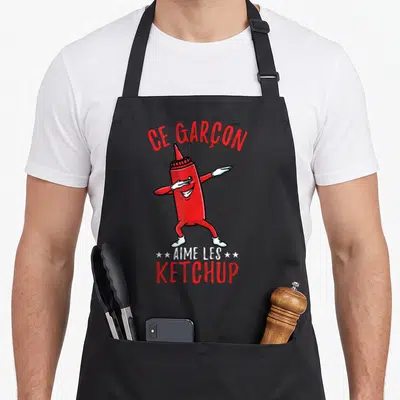 Tablier de cuisine noir avec illustration d'un bocal de ketchup rouge effectuant un mouvement de danse moderne.