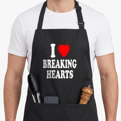 Tablier de cuisine noir avec inscription I Love Breaking Hearts et un grand cœur rouge au centre du design imprimé.