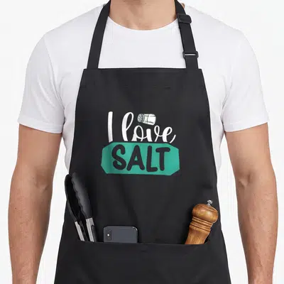 Tablier de cuisine noir avec inscription I love SALT et illustration de poivrier blanc sur bande turquoise.