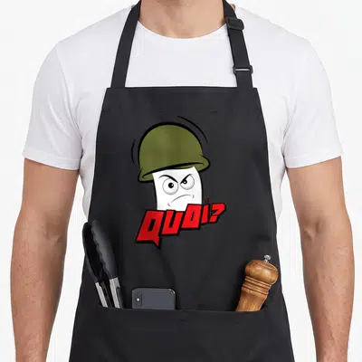 Tablier de cuisine noir avec un personnage blanc en casque vert et le texte Quoi ? en lettres rouges stylisées.