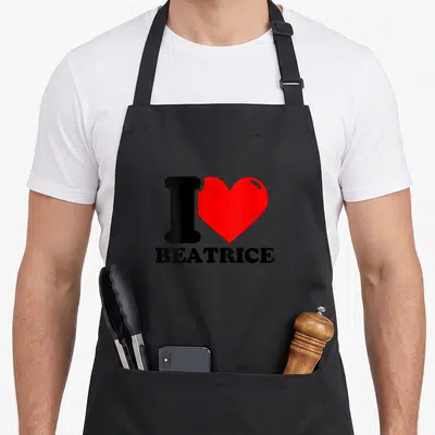 Tablier de cuisine noir avec un grand cœur rouge et le texte J'ADORE BEATRICE imprimé en noir au centre.
