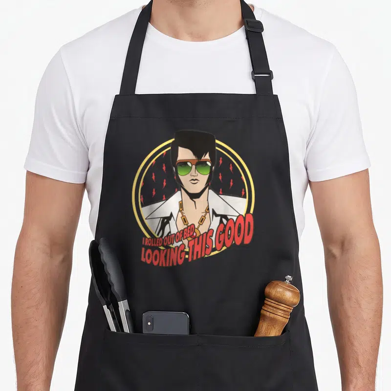 Tablier de cuisine noir avec illustration d'Elvis aux lunettes vertes et texte rouge I rolled out of bed looking this good.