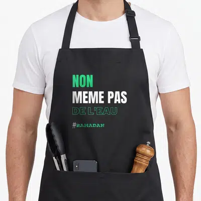Tablier de cuisine noir avec l'inscription Non même pas de l'eau et le mot Ramadan en vert.