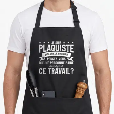 Tablier de cuisine noir avec inscription blanche humoristique sur la profession de plaquiste et des étoiles décoratives en haut.