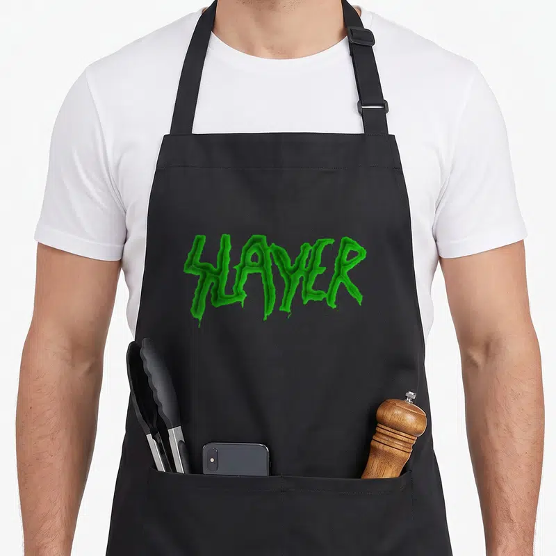 Tablier de cuisine noir avec le mot SLAYER imprimé en vert acide style lettering métallique.