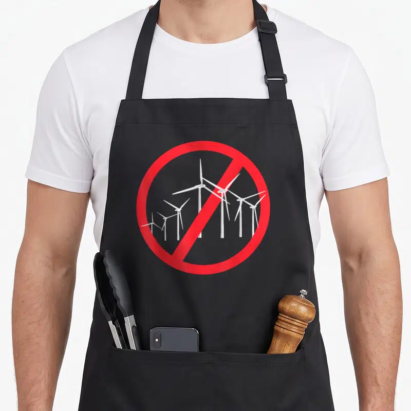 Tablier de cuisine noir avec un panneau d'interdiction rouge sur des éoliennes blanches et du texte.