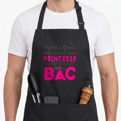 Tablier de cuisine noir avec inscription Voici à Quoi Ressemble Une Princesse Bac en rose et gris, toque et rouleau de diplôme.