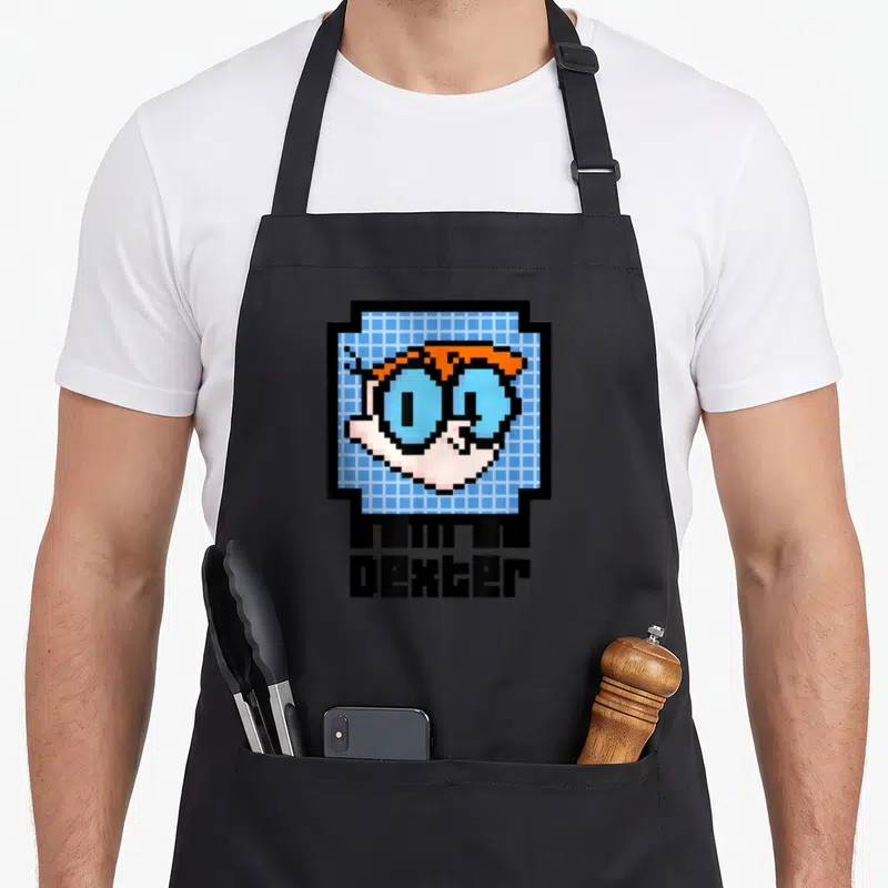 Tablier de cuisine noir avec un chip pixelisé montrant le visage de Dexter et son nom en dessous.