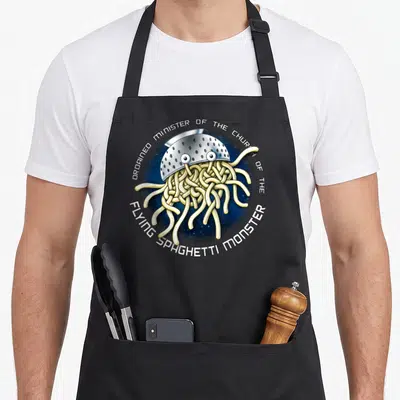 Tablier de cuisine noir avec illustration colorée d'un monstre spaghetti sous colador et texte circulant autour.