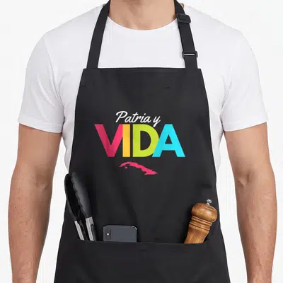 Tablier de cuisine noir avec le texte Patria y Vida en couleurs vives et une carte rose de Cuba sous les lettres.