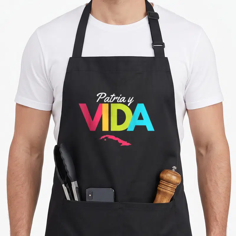 Tablier de cuisine noir avec le texte Patria y Vida en couleurs vives et une carte rose de Cuba sous les lettres.