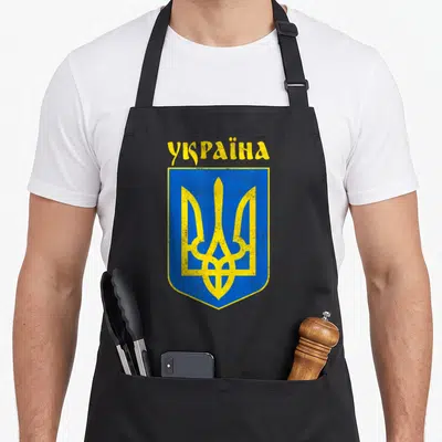 Tablier de cuisine noir avec les armoiries ukrainiennes et l'inscription en jaune sur fond bleu.