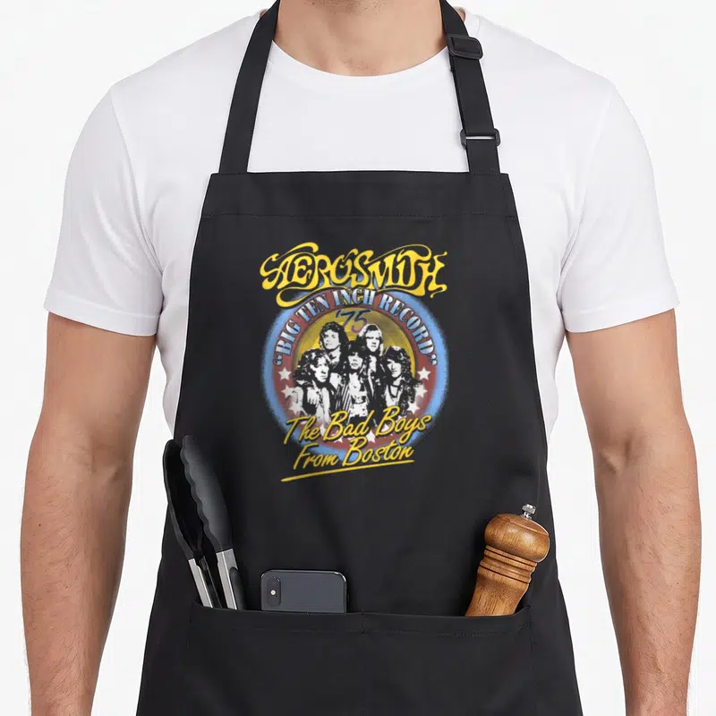 Tablier de cuisine noir avec illustration circulaire Aerosmith et le texte The Bad Boys From Boston en jaune et blanc.