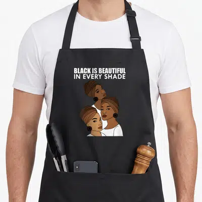 Tablier de cuisine noir avec illustration de trois femmes afro au turban et texte blanc Black is beautiful in every shade