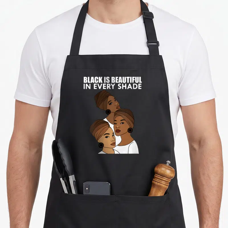 Tablier de cuisine noir avec illustration de trois femmes afro au turban et texte blanc Black is beautiful in every shade