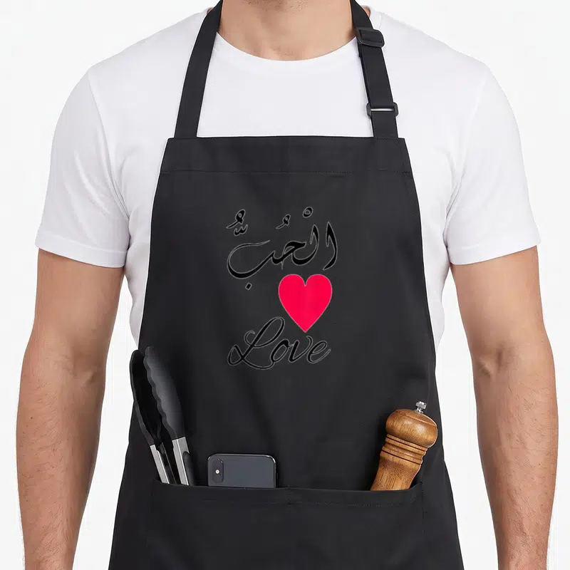 Tablier de cuisine noir avec calligraphie arabe, cœur rose et mot Love en écriture cursive.