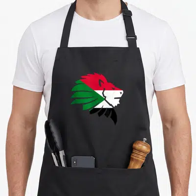 Tablier de cuisine noir avec tête de lion aux couleurs du drapeau soudanais en rouge, blanc, noir et vert.