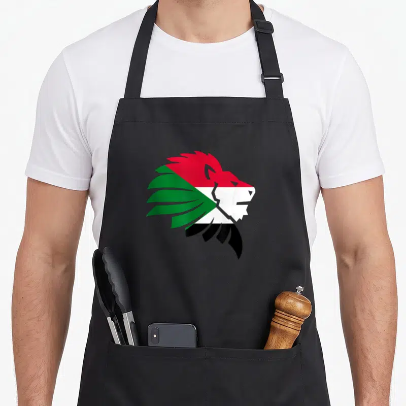 Tablier de cuisine noir avec tête de lion aux couleurs du drapeau soudanais en rouge, blanc, noir et vert.