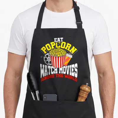 Tablier de cuisine noir avec illustration de popcorn, pellicule et texte Eat Popcorn Watch Movies Ignore The World.