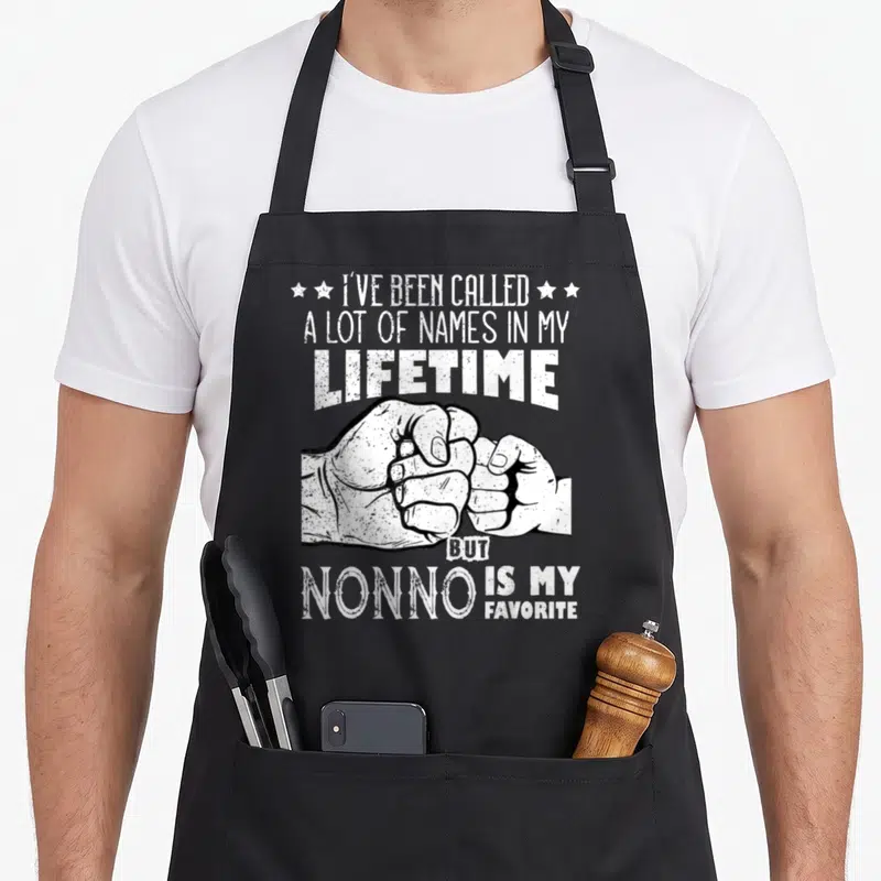 Tablier de cuisine noir avec inscription blanche sur le poing d'un grand-père et d'un enfant qui se serrent la main.